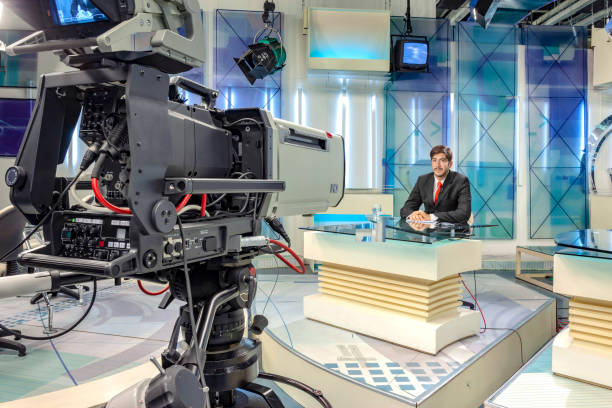 Television host in studio reading the news in front of camera