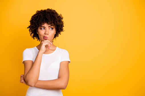 Close up photo beautiful amazed she her dark skin lady arms hands chin think over not sure homework diligent student look empty space wearing casual white t-shirt isolated yellow bright background