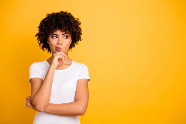 close up photo beautiful amazed she her dark skin lady arms hands chin think over not sure homework diligent student look empty space wearing casual white t-shirt isolated yellow bright background - uncertainty imagens e fotografias de stock