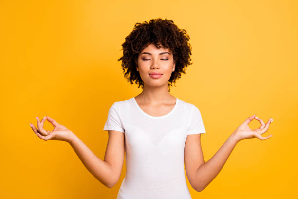 Portrait of her she nice cute attractive charming calm peaceful wavy-haired girl wearing casual white t-shirt showing om sign closed eyes isolated on bright vivid shine yellow background Portrait of her she nice cute attractive charming calm peaceful wavy-haired girl wearing casual white t-shirt showing om sign closed eyes isolated on bright vivid shine yellow background. meditation hands stock pictures, royalty-free photos & images