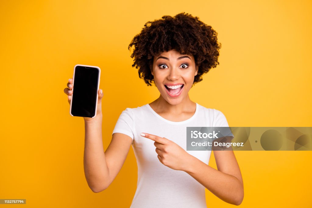 Portrait of her she nice attractive lovely charming cheerful cheery ecstatic wavy-haired lady holding in hands cell showing black screen isolated on bright vivid shine yellow background Portrait of her she nice attractive lovely charming cheerful cheery ecstatic wavy-haired lady holding in hands cell showing black screen isolated on bright vivid shine yellow background. Mobile Phone Stock Photo