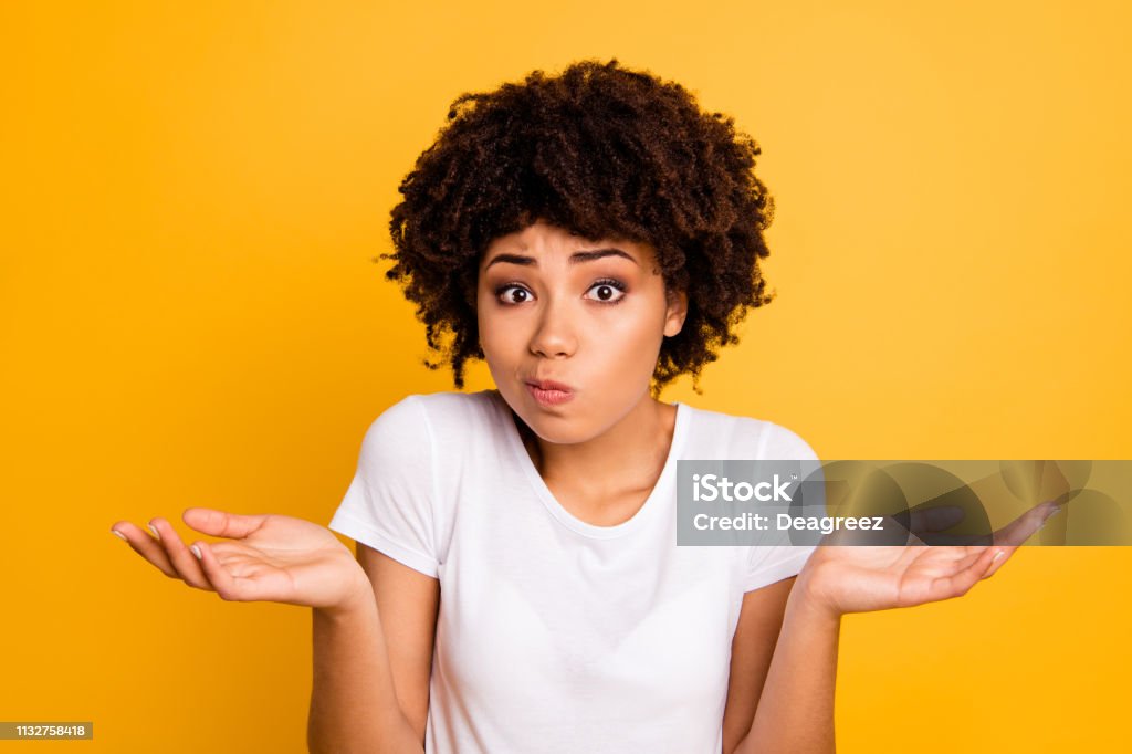 Close-up portrait of her she nice attractive puzzled ignorant wavy-haired girl showing gesture no information isolated on bright vivid shine yellow background Close-up portrait of her she nice attractive puzzled ignorant wavy-haired girl showing gesture no information isolated on bright vivid shine yellow background. Confusion Stock Photo