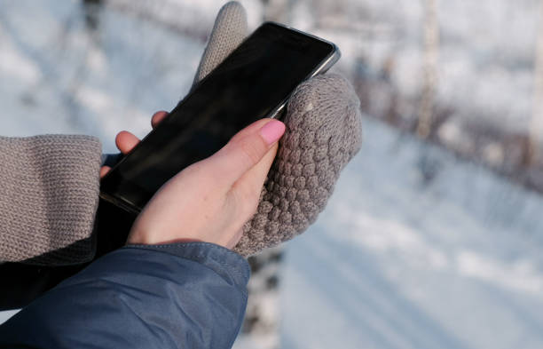 istock Close-up woman's hands in mittens writing messages on cellphone in winter park. 1132761604