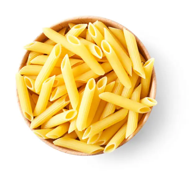 Delicious pasta or penne noodles, isolated on white background. Top view scene, healthy eating or healthy lifestyle. Penne pasta or macaroni in a wooden bowl, italian cuisine.