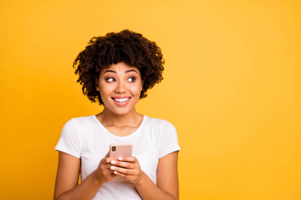 portrait of her she nice cute attractive lovely charming cheerful cheery wavy-haired lady holding in hands cell looking aside isolated on bright vivid shine yellow background - aside imagens e fotografias de stock