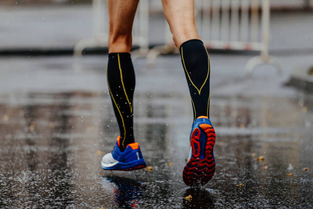 feet male runner in compression socks feet male runner in compression socks running on wet asphalt number 42 stock pictures, royalty-free photos & images