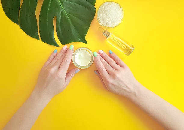 istock female hands manicure, cosmetic cream, monstera leaf, on a yellow background 1132764603