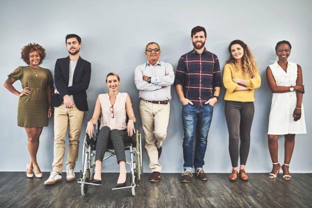 We're all qualified! Shot of a diverse group of businesspeople standing against a wall mixed age range photos stock pictures, royalty-free photos & images