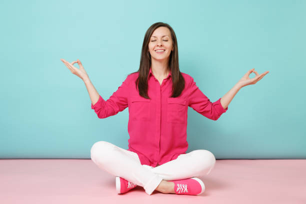 Full length portrait of smiling young woman in rose shirt blouse, white pants sitting on floor isolated on bright pink blue pastel wall background studio Fashion lifestyle concept. Mock up copy space retrato de longitud completa de mujer joven sonriente en blusa de camisa rosa, pantalones blancos sentados en el suelo aislado en el estudio de fondo de pared azul pastel rosa brillante. concepto de estilo de vida de moda. maqueta de espacio de copia