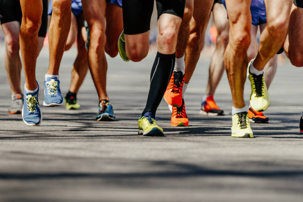 group legs runners athletes group legs runners athletes run on asphalt road marathon marathon stock pictures, royalty-free photos & images