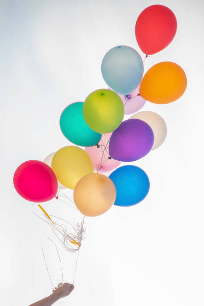 istock Hand holding colorful balloon bunch on white background. 1132766980