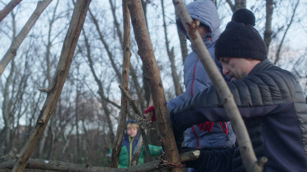 istock Father building teepee with sons. Riverside in the city 1132767526