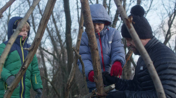 istock Father building teepee with sons. Riverside in the city 1132767532
