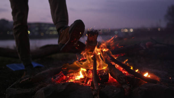 istock Lone man burning campfire on a riverside. Warming up feet 1132767625