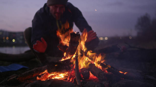istock Lone man burning campfire on a riverside. Warming up hands 1132767660