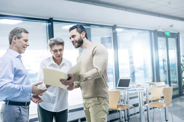 istock Handsome bearded man showing some papers to elderly couple indoors 1132768192