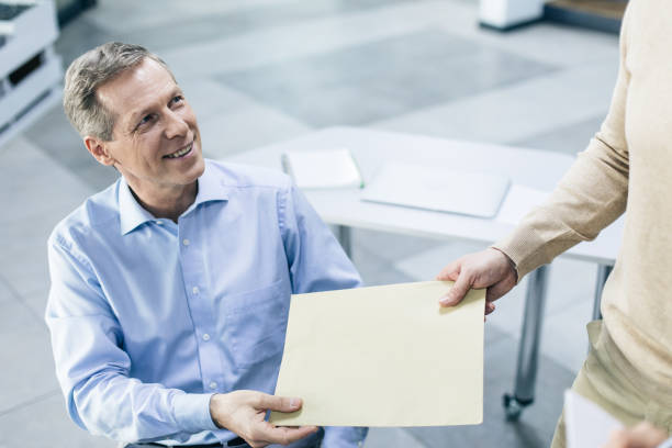 istock Gray-haired man taking papers in arms while looking up at his neighbour 1132768314
