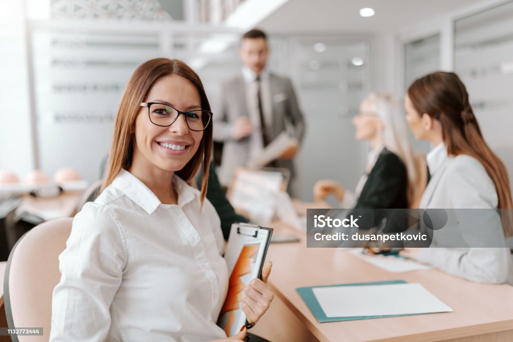 Portrait of beautiful Caucasian brunette sitting at meeting in board room and holding clipboard. Excellence is not a destination, it's a journey that never ends. Organization Stock Photo