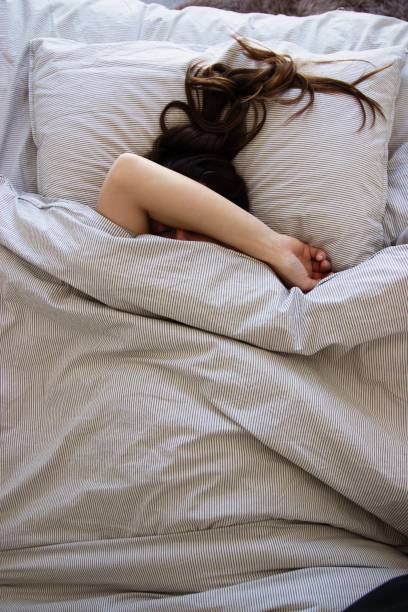 istock Sleeping woman in bed with hand in front of her face 1132774229