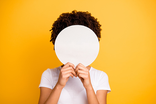 Close up photo beautiful amazing she her dark skin lady hiding face round circle banner placard do not want be recognized wear casual white t-shirt isolated yellow bright vibrant vivid background.