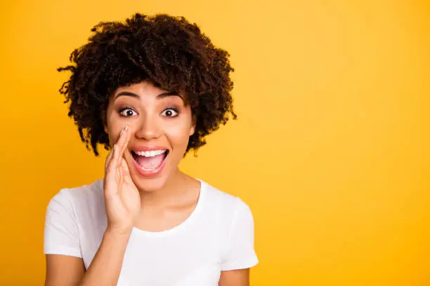 Close up photo beautiful amazing she her dark skin lady hand mouth send share spread information messages excited wear casual white t-shirt isolated yellow bright vibrant vivid background.