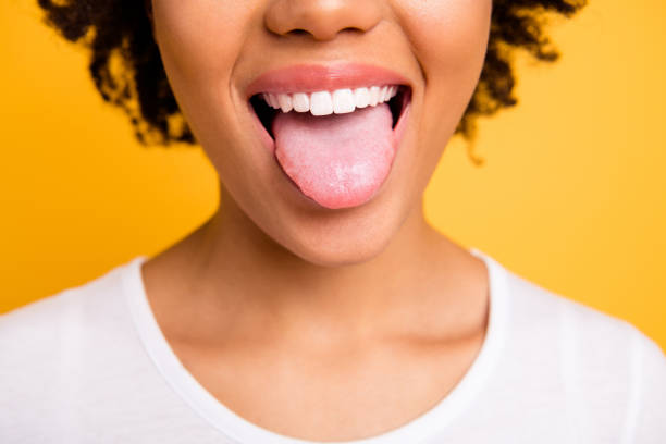 Cropped close up photo beautiful amazing she her dark skin lady beaming whitening toothy smile tongue out perfect mouth wear casual white t-shirt isolated yellow bright vibrant background Cropped close up photo beautiful amazing she her dark skin lady beaming whitening toothy smile tongue out perfect mouth wear casual white t-shirt isolated yellow bright vibrant background. human tongue stock pictures, royalty-free photos & images