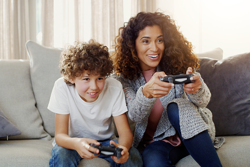 Shot of a young mother and her son playing video games together at home