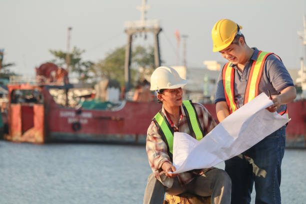 istock Asian male architects with blueprint working at construction site with safety helmet. 1132782351