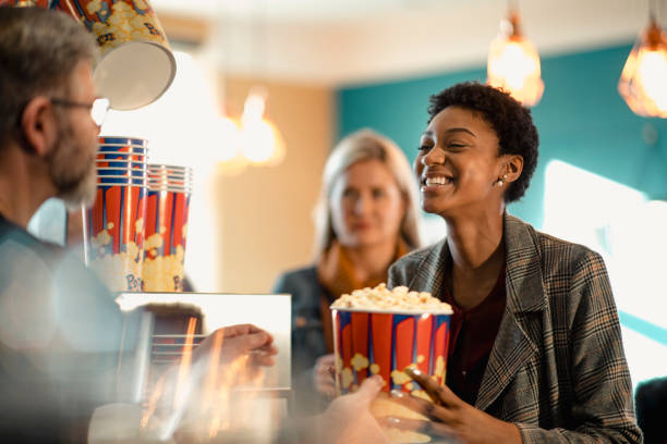 Excited for Her Popcorn Young female woman buying popcorn at the concession stand while at the movies. She is being passed the popcorn by the customer assistant. concession stand stock pictures, royalty-free photos & images