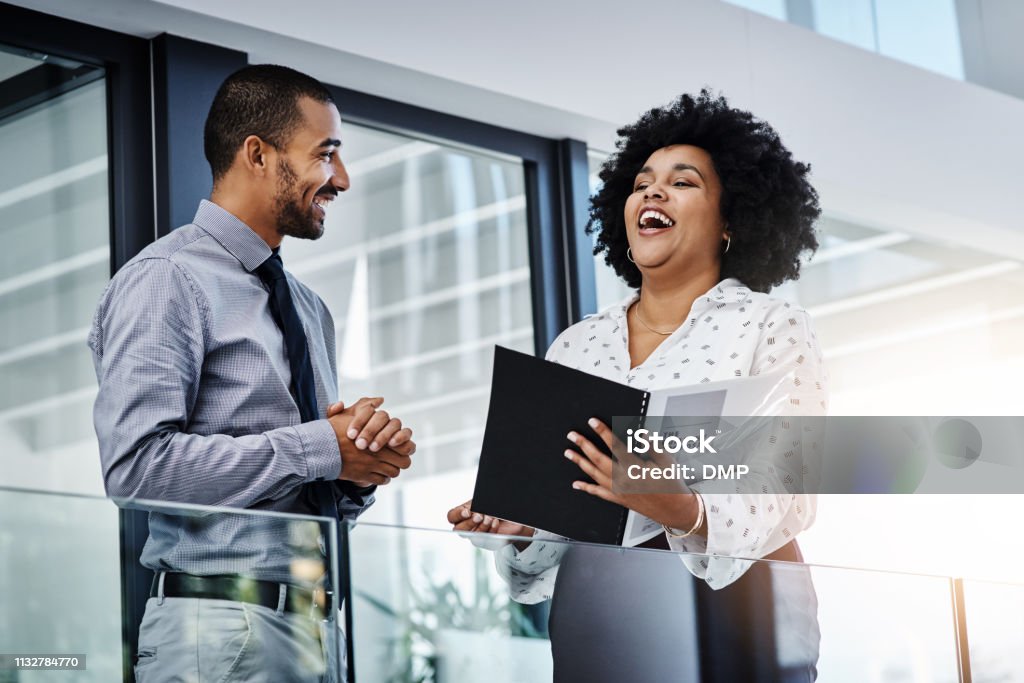 This ism awesome news! Shot of a businessman and businesswoman discussing paperwork in a modern office Laughing Stock Photo