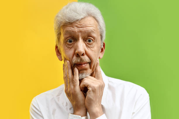 istock The senior man looking suprised isolated on color studio background 1132785797