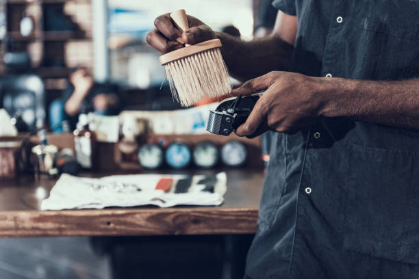 Hair stylist preparing barber tool to working Cropped photo of calm master standing near workplace indoor barbershop. He cleaning working tool using soft brush black barber stock pictures, royalty-free photos & images