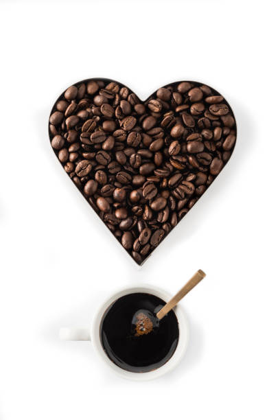 istock Coffee beans in a Heart Shape Cookie Cutter Isolated on a white background and one cup of coffee 1132790752