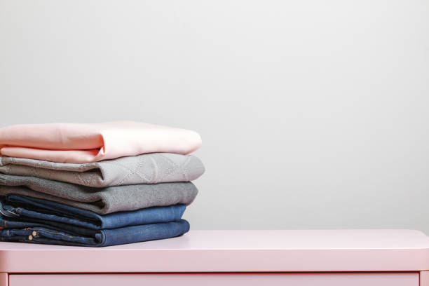 istock On a pink table is a stack of folded clothes. Gray background. Close-up 1132792960
