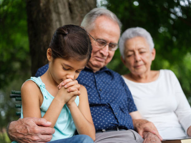 kleines mädchen betet mit ihren großeltern - grandparent grandfather granddaughter little girls stock-fotos und bilder