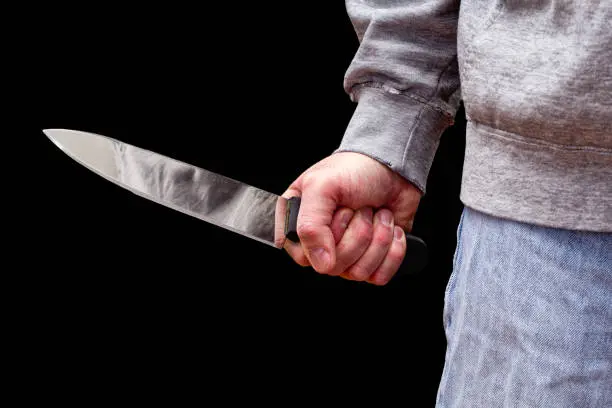 Man brandishing kitchen knife in a threatening manner. Isolated on black.