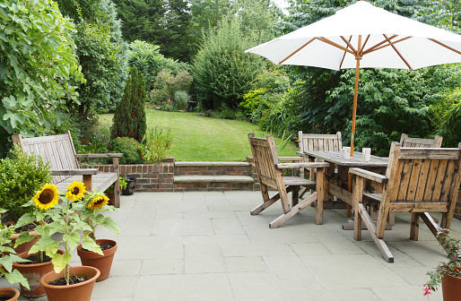 Outdoors shot of a picnic table and chairs in a terrace. Food, sandwiches and fresh fruit served on plates. No people.