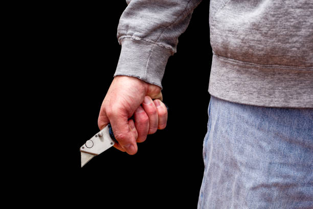Man Brandishing Knife Man brandishing box knife in a threatening manner. Isolated on black. box cutter knife stock pictures, royalty-free photos & images