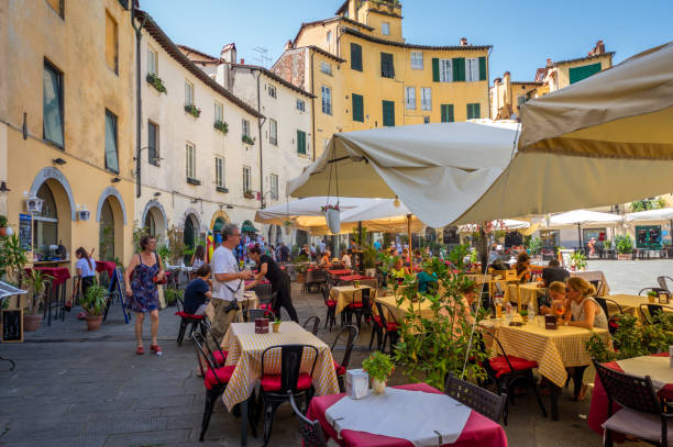 Piazza Anfiteatro in Lucca, Tuscany. Italy Lucca, Italy - August 2, 2017: panorama of the Piazza Anfiteatro in the middle of lucca, Tuscany, Italy. Tourists walk over the place or sitting at one of the many cafes lucca italy stock pictures, royalty-free photos & images