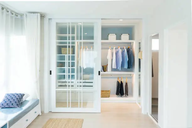 Photo of Stylish clothes and accessories in large wardrobe closet