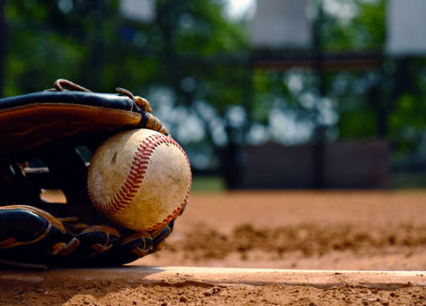 Baseball in glove on team field. Baseball in glove laying on pitcher's mound of ball field.  Old used sports equipment for team sport. baseball ball photos stock pictures, royalty-free photos & images