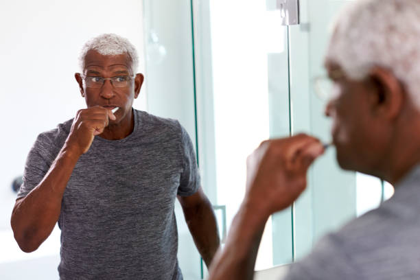 istock Senior Man Looking At Reflection In Bathroom Mirror Wearing Pajamas Brushing Teeth 1132797523