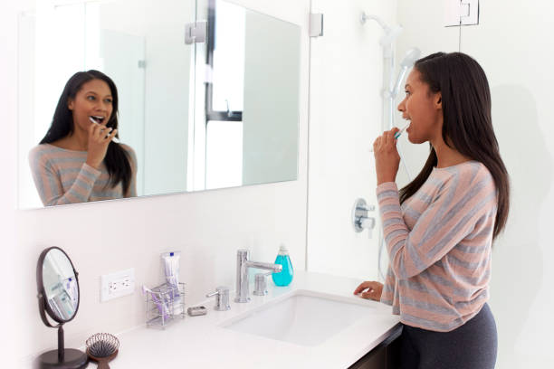 istock Woman Looking At Reflection In Bathroom Mirror Brushing Teeth 1132798198