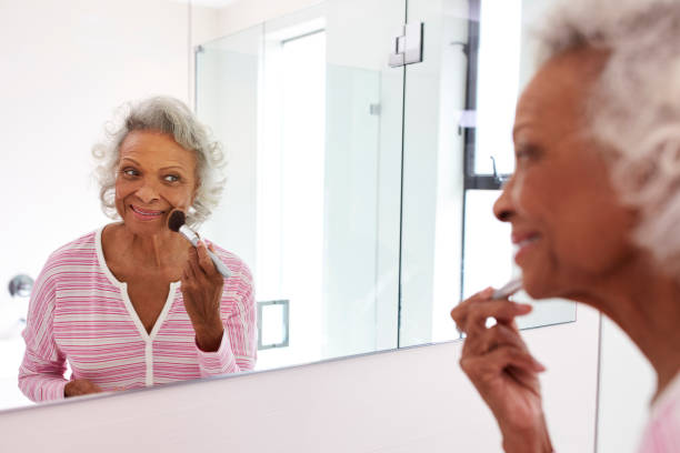 istock Senior Woman Looking At Reflection In Bathroom Mirror Putting On Make Up 1132799117