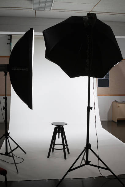 istock Empty photo studio with lighting equipment, white background and chair. 1132799498