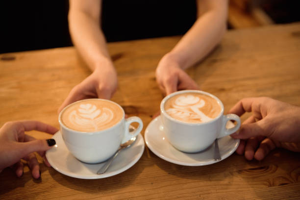 istock Friendly bartender serving espresso coffee to customers in the interior of a modern coffee shop. 1132807857