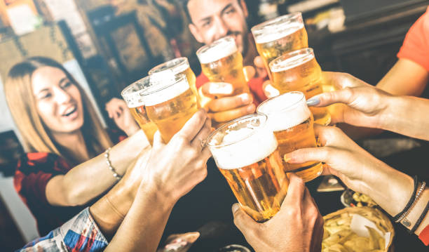 friends drinking beer at brewery bar restaurant on weekend - friendship concept with young people having fun together toasting brew pint on happy hour at pub - focus on glass - bright contrast filter - irish culture beer drinking pub imagens e fotografias de stock