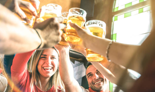 friends drinking and toasting beer at brewery bar restaurant - friendship concept on young millenial people having fun together on happy hour at brew pub - focus on girl face - summer sunshine filter - beer pub women pint glass imagens e fotografias de stock