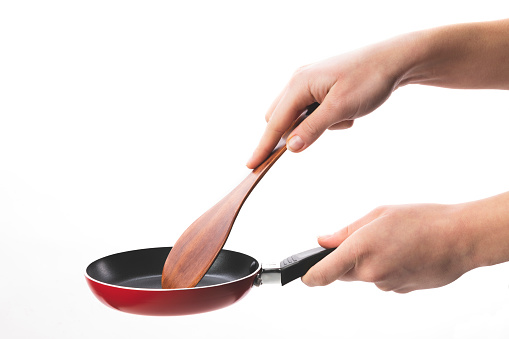 Hands with frying pan and spoon cooking. cut out