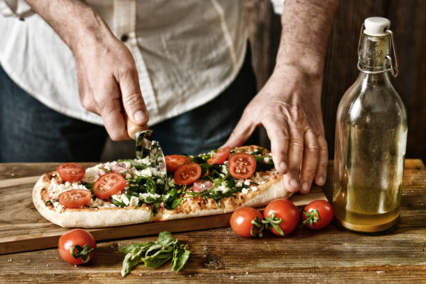 pokroić pizzę z pomidorów, rukoli i mozzarelli - tradycyjna rzymska pizza - efekt desaturacji - selektywne skupienie - zbliżenie - pizza one person service human hand zdjęcia i obrazy z banku zdjęć